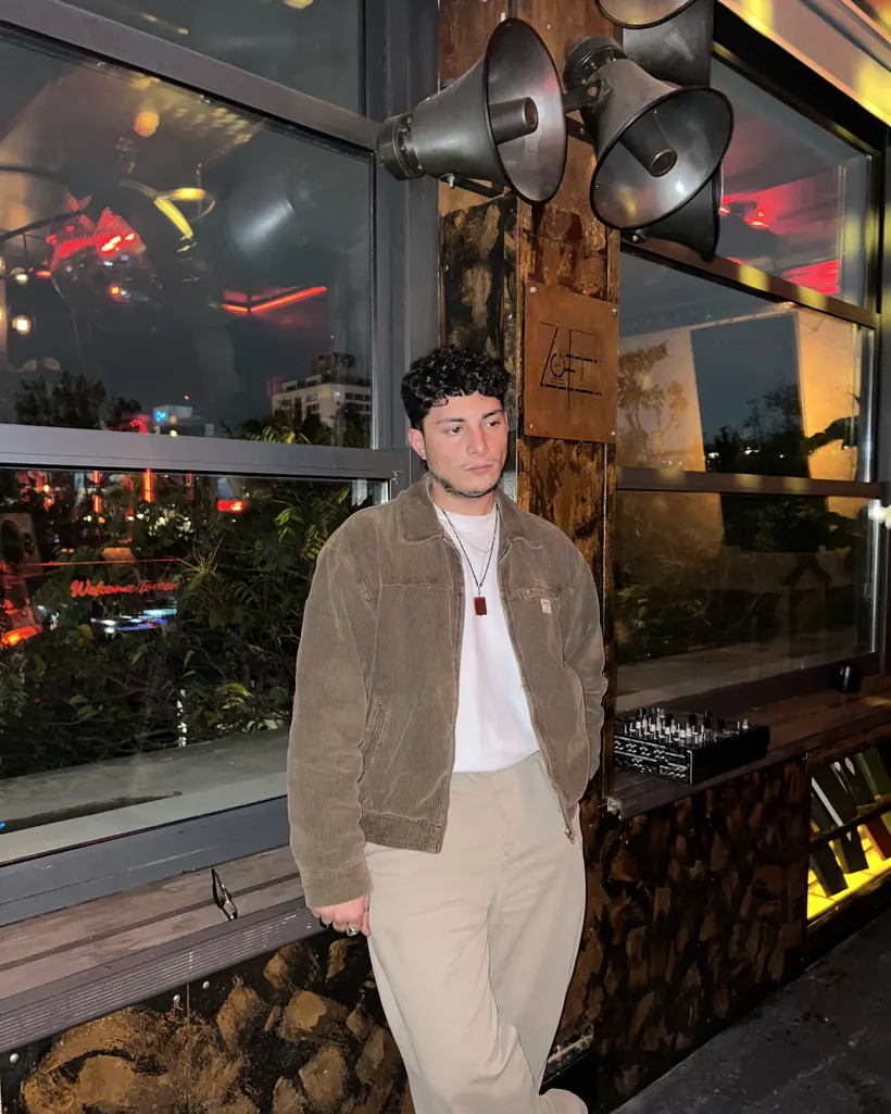 Senan Qulamov leaning against a wooden wall at night in Baku